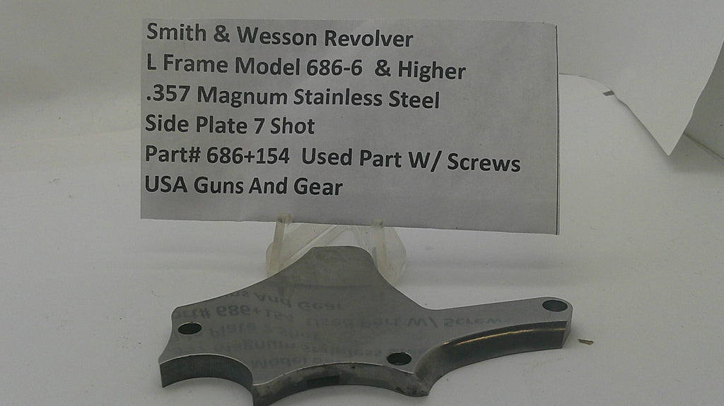 A used metal firearm part for a Smith & Wesson Revolver, displayed on a clear stand with a paper label card showing part details.