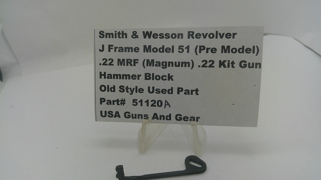 A small black metal hammer block part displayed on a clear stand in front of a white sign that reads 'Smith & Wesson Revolver J Frame Model 51 (Pre Model) .22 MRF (Magnum) .