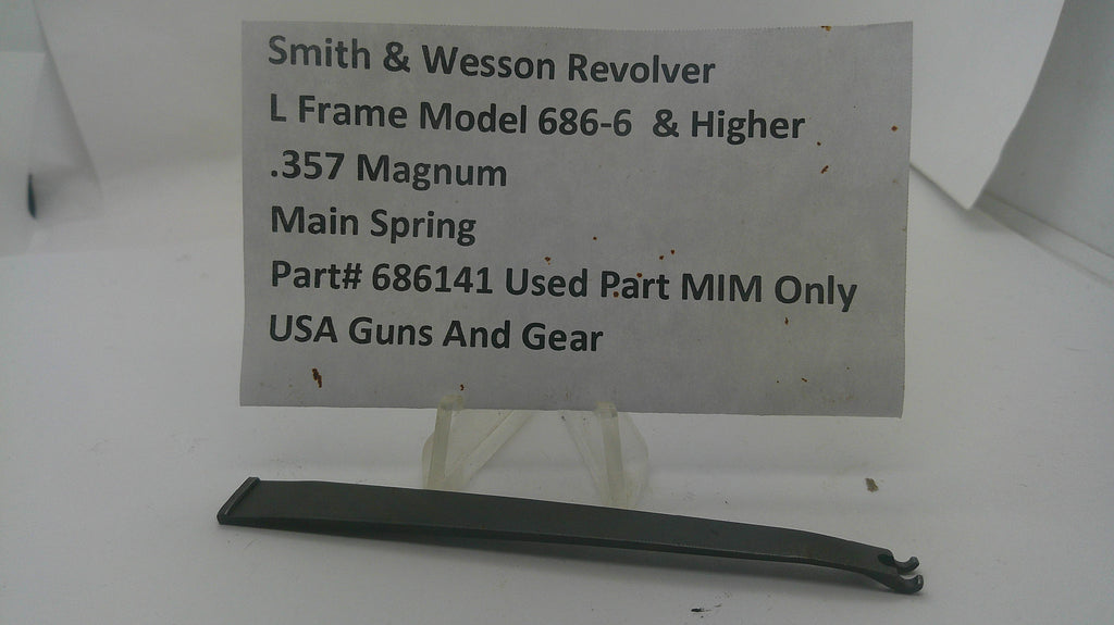A used black metal main spring for a Smith & Wesson revolver, displayed on a clear plastic stand with a white paper label showing the part number and model details.