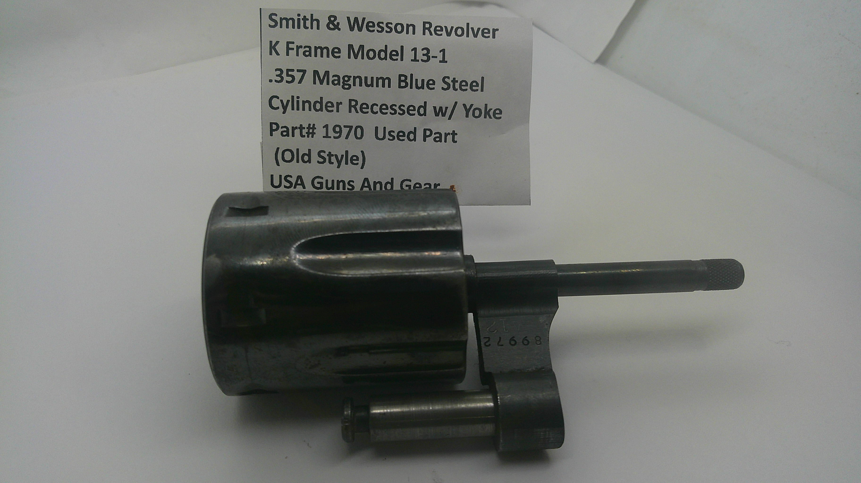 A used metal revolver cylinder component, identified as a Smith & Wesson Model 13-1 .357 Magnum blue steel cylinder with a yoke, displayed on a white background with a paper label.