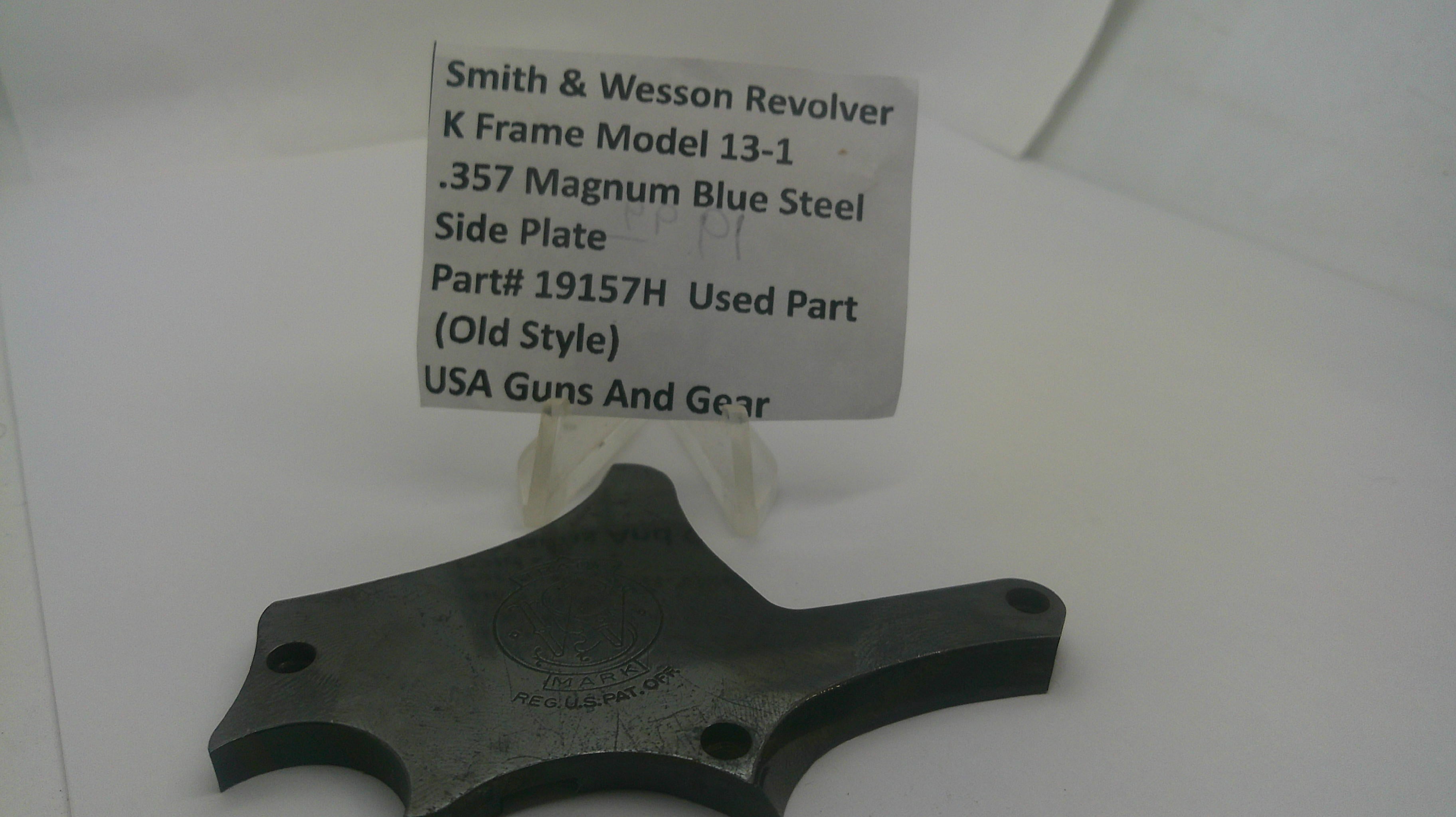 A used metal side plate part for a Smith & Wesson revolver, mounted on a clear plastic display stand with a paper label showing the part details.