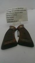 A pair of vintage wooden gun grips with a small metal pin and a white paper tag showing part details, photographed on a white background.
