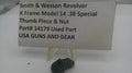 A used black metal Smith & Wesson revolver thumb piece and nut part, displayed on a small clear stand in front of a white sign with black text identifying it as a used part.