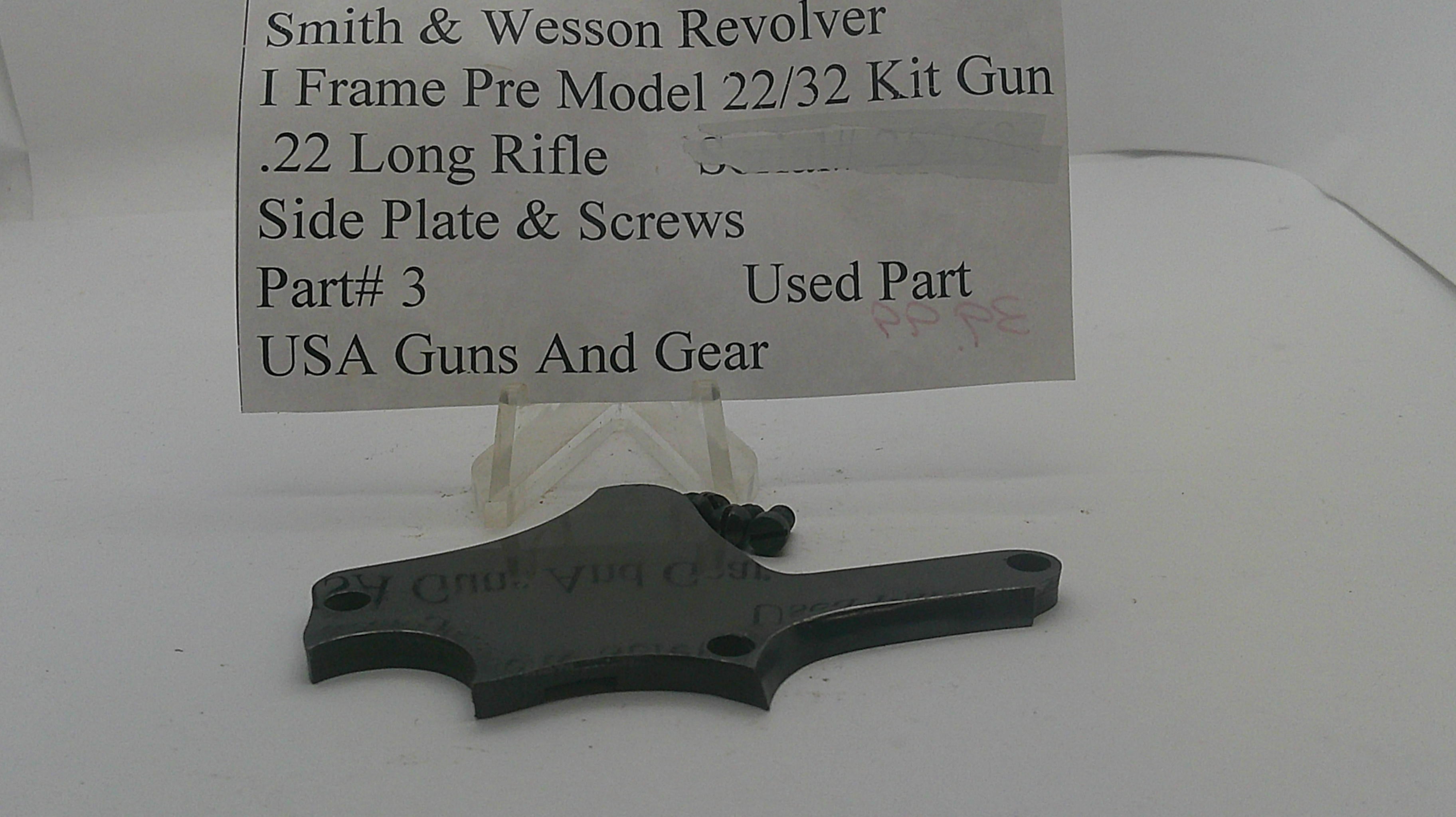A used black metal side plate and screws kit for a Smith & Wesson revolver, displayed on a clear plastic stand with a paper label card. The label reads 'Smith & Wesson Revolver I Frame Pre Model 22/32 Kit Gun .