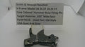 A used metal hammer nose part for a Smith & Wesson revolver, displayed on a white surface with a handwritten label card above it.