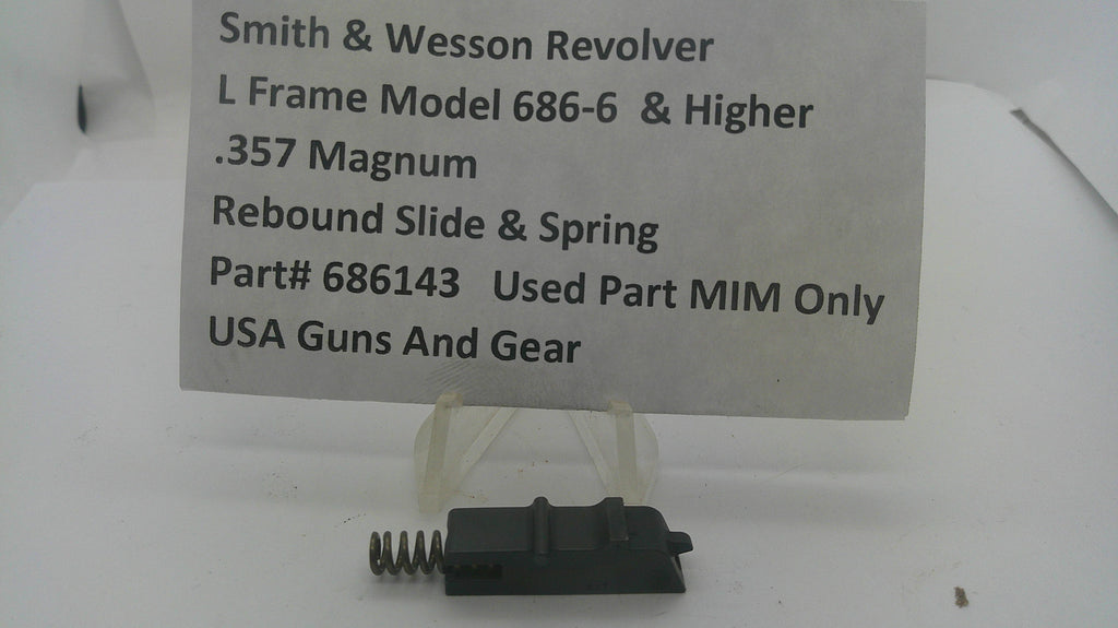 A used black metal Smith & Wesson revolver rebound slide and spring part, displayed on a clear plastic stand with a white paper label card in the background.