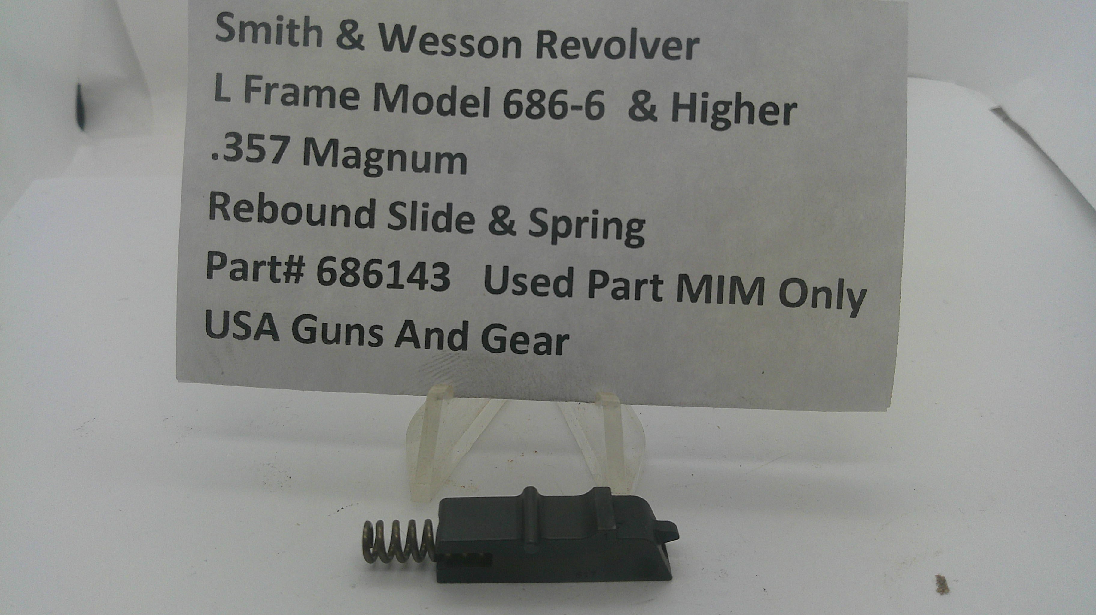 A used black metal Smith & Wesson revolver rebound slide and spring part, displayed on a clear plastic stand with a white paper label card in the background.