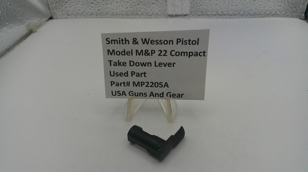 Smith & Wesson pistol take-down lever on a white surface with a label.