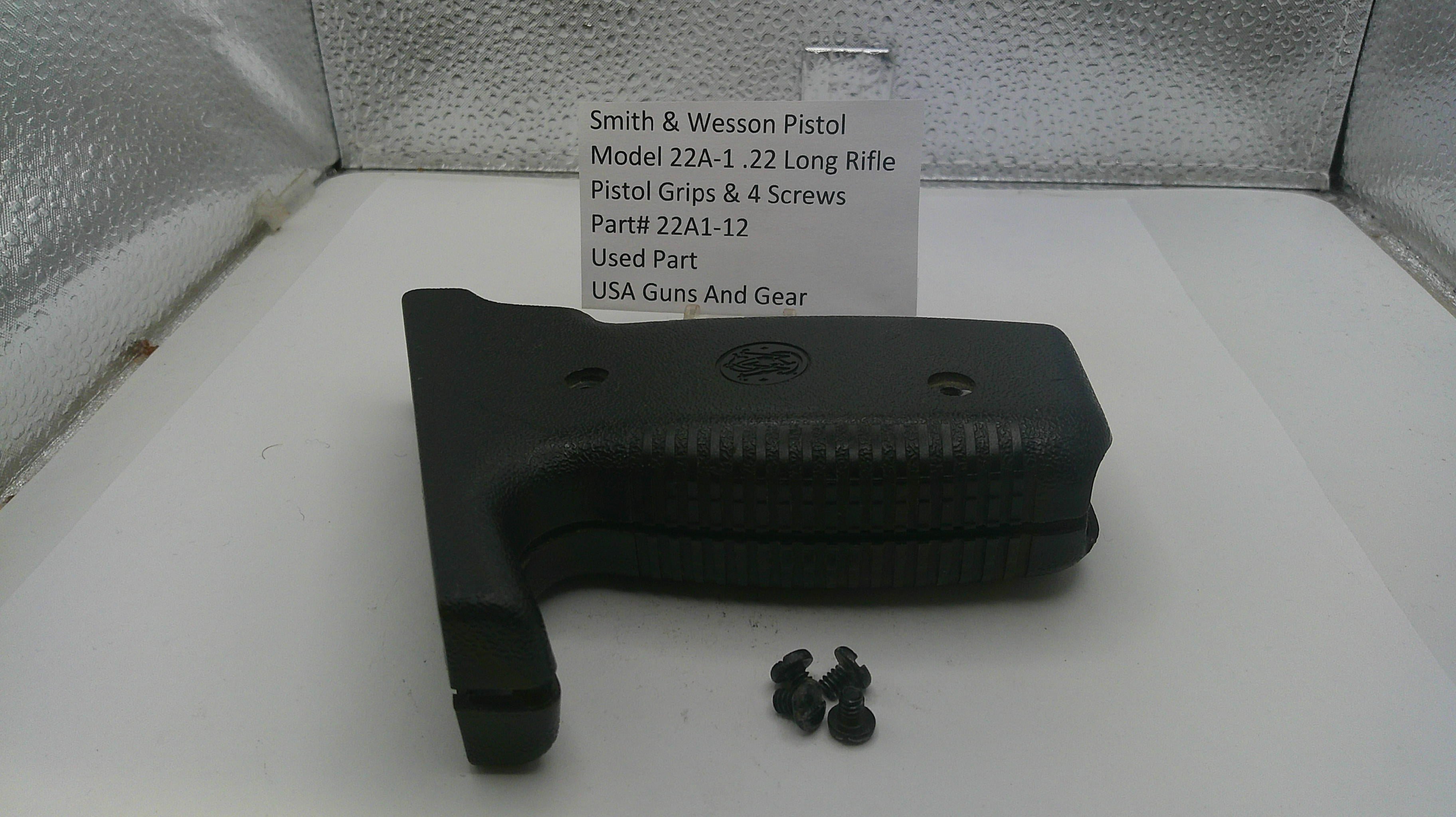 Black pistol grip and screws on a white surface with a label in the background.