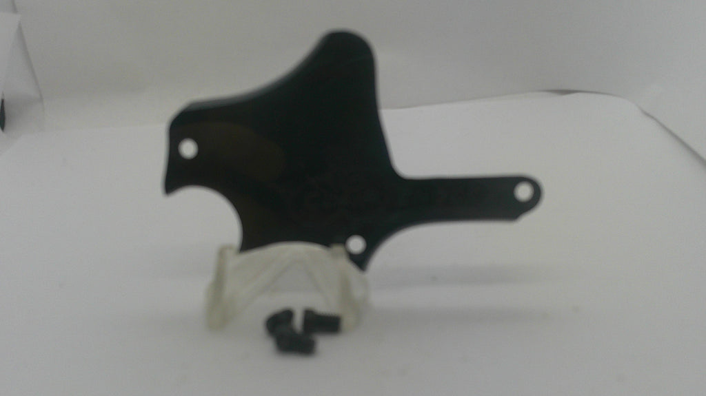 A black plastic guitar pickguard with mounting holes, displayed on a white surface with a small white plastic clip and black screws in front.
