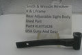 A used black metal part for a Smith & Wesson revolver rear adjustable sight body, displayed on a clear stand with a white label card showing part details.