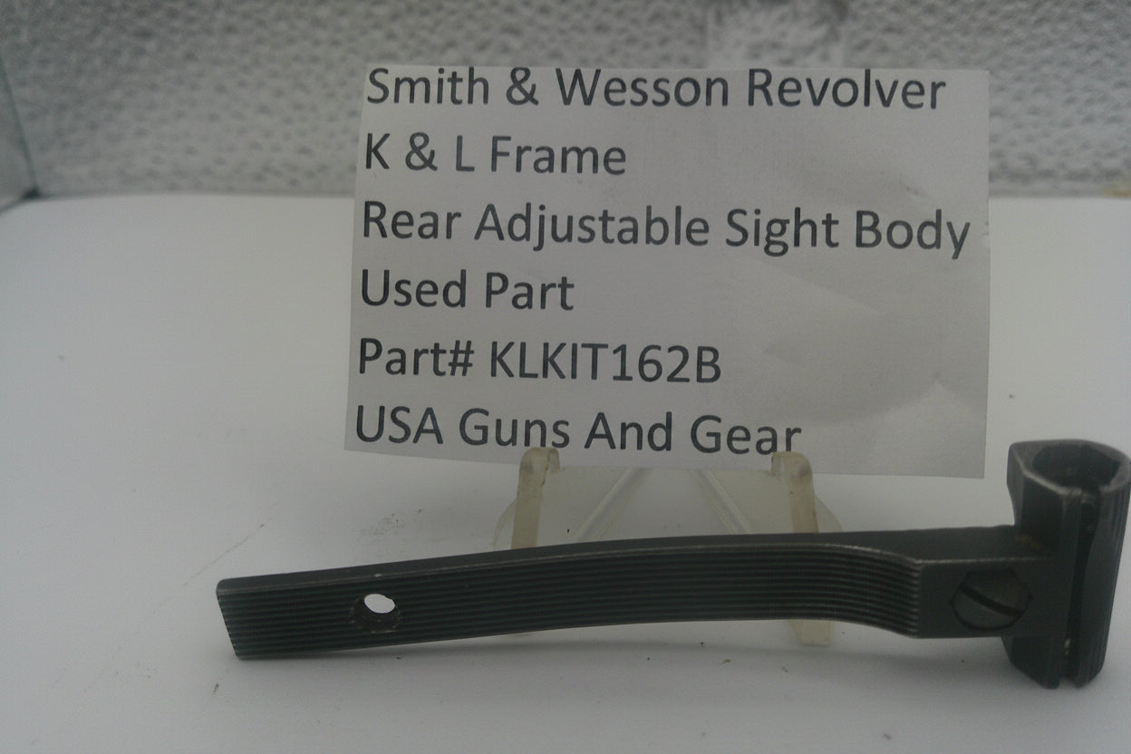A used black metal part for a Smith & Wesson revolver rear adjustable sight body, displayed on a clear stand with a white label card showing part details.