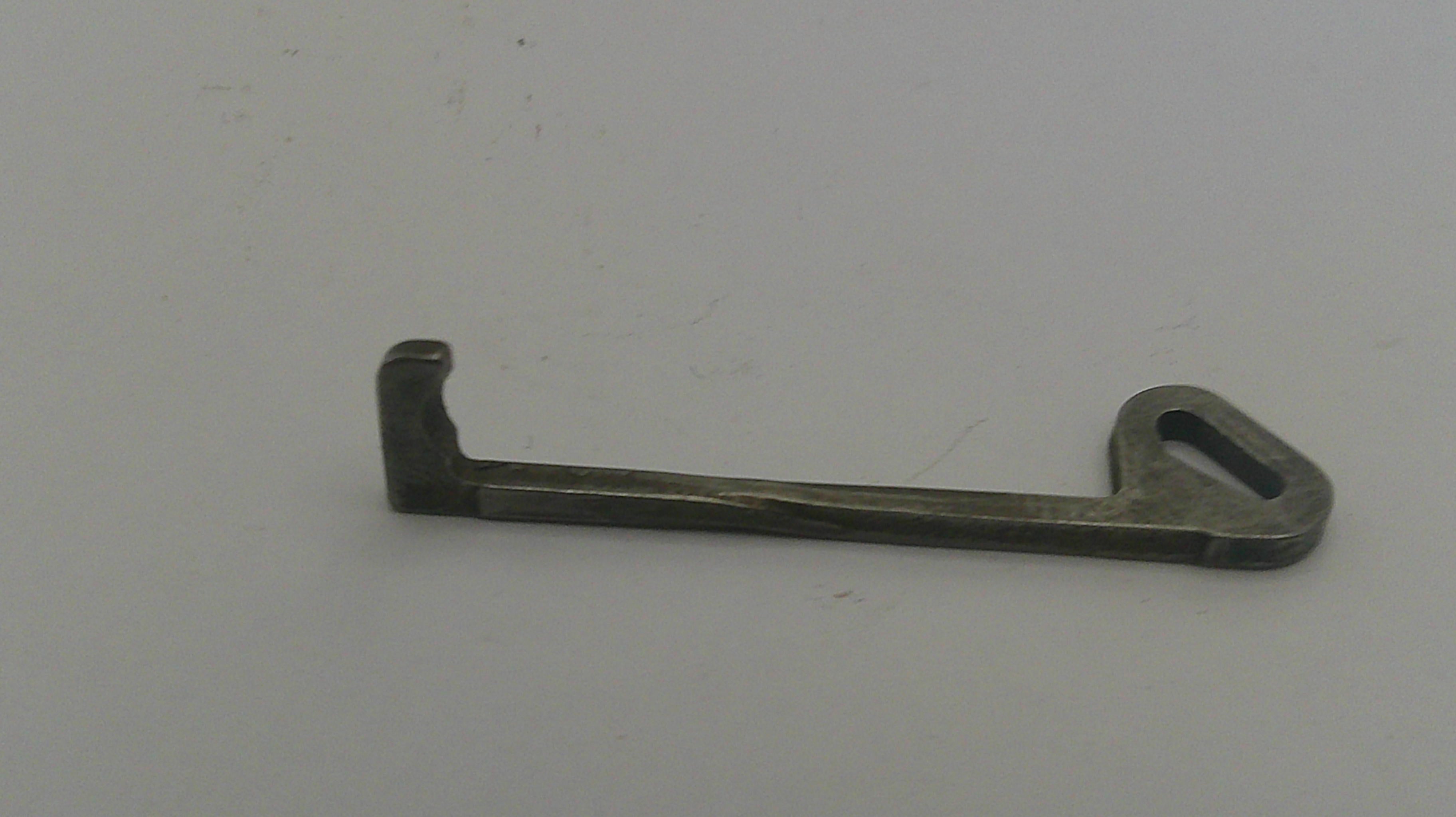 Metallic key-like object on a light gray background