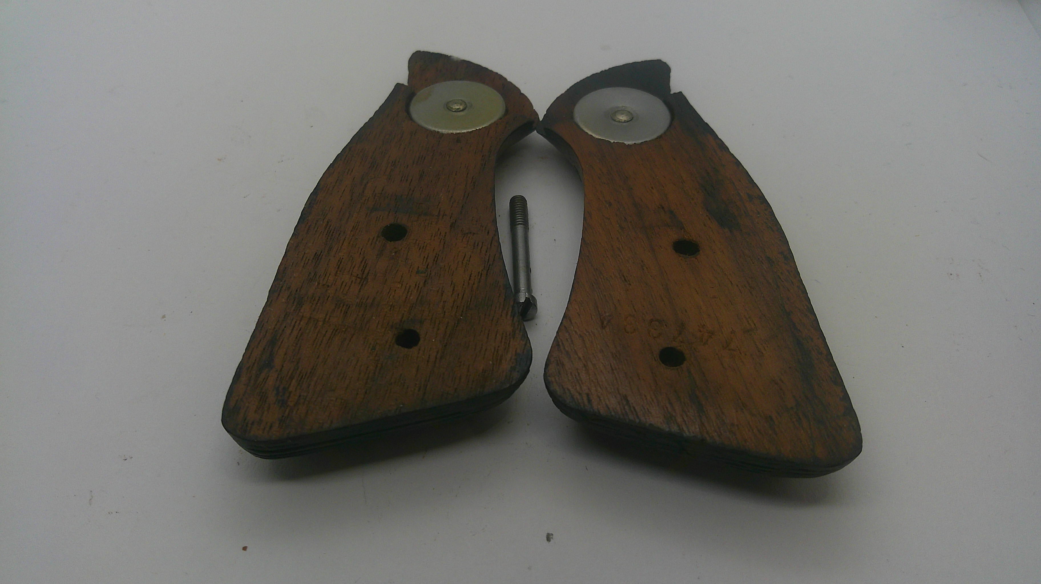 A pair of vintage wooden knife guard halves with metal circular inserts and a small metal pin, shown on a plain light background.