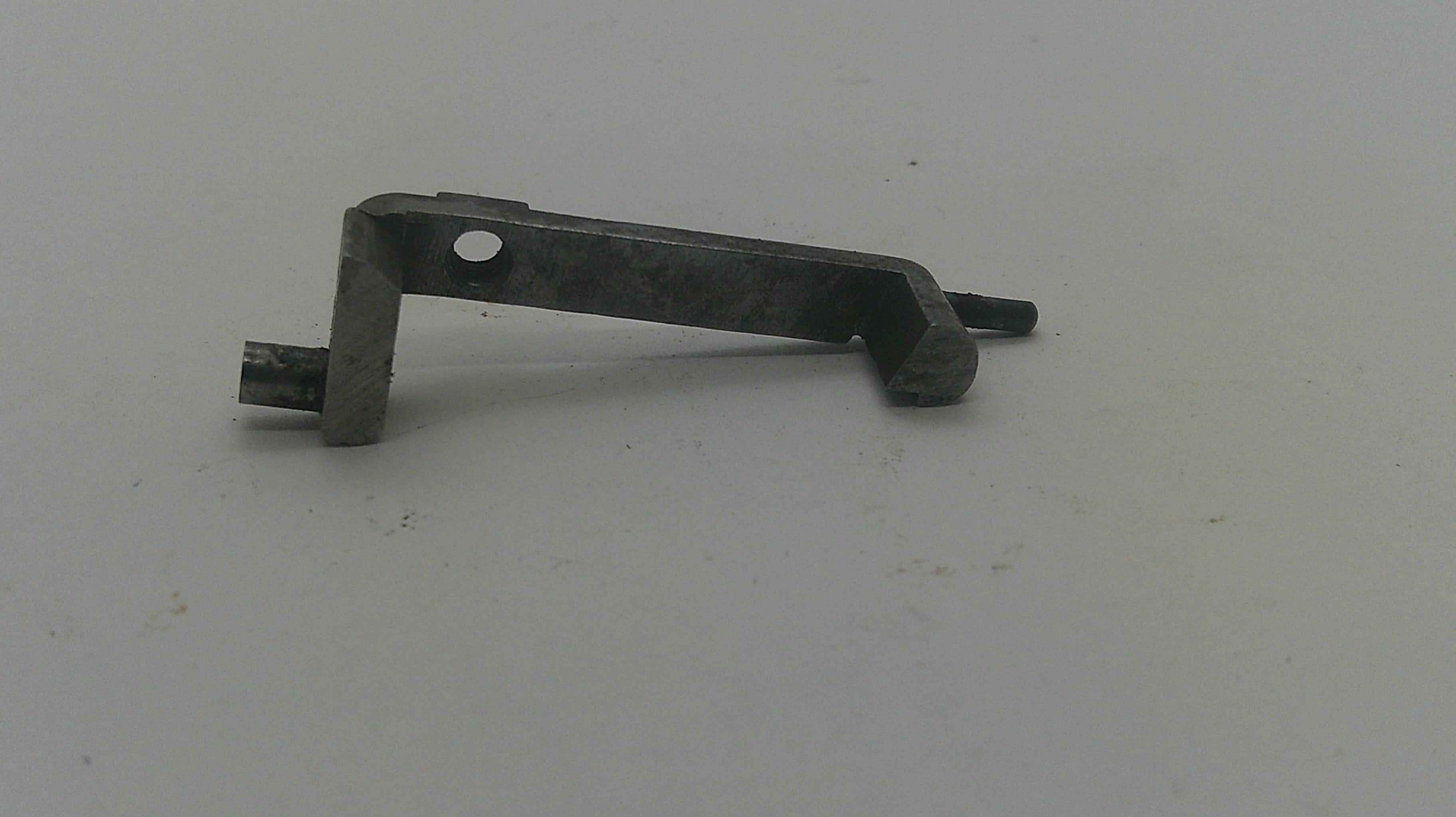 A small dark metal hardware piece with a circular hole and a protruding pin, photographed on a plain light background.