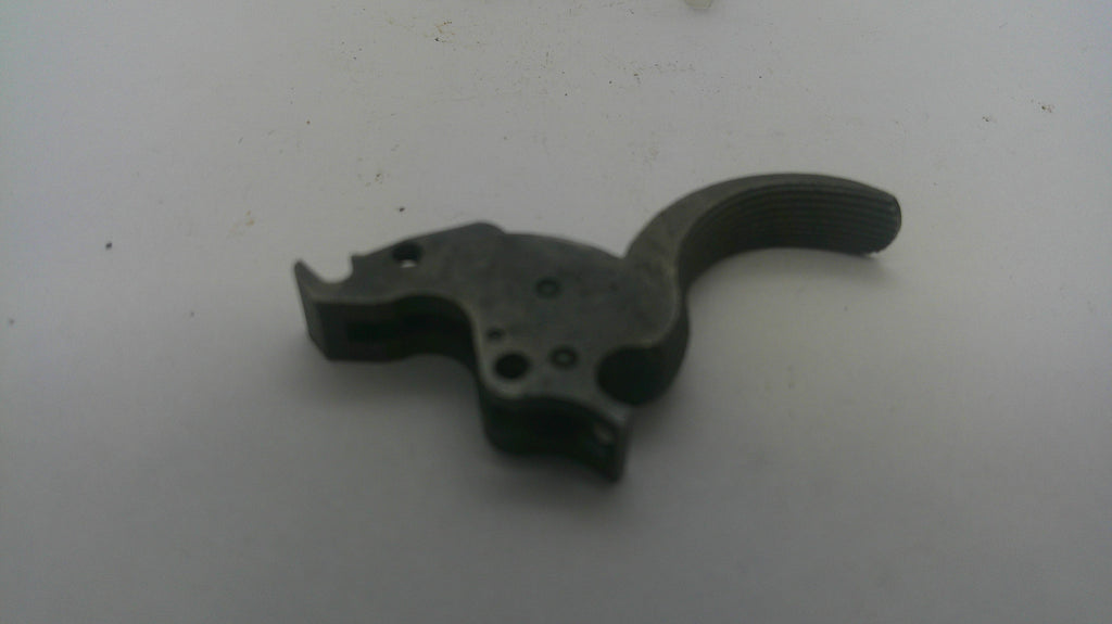 A dark metal firearm trigger assembly component, photographed on a plain light gray surface.