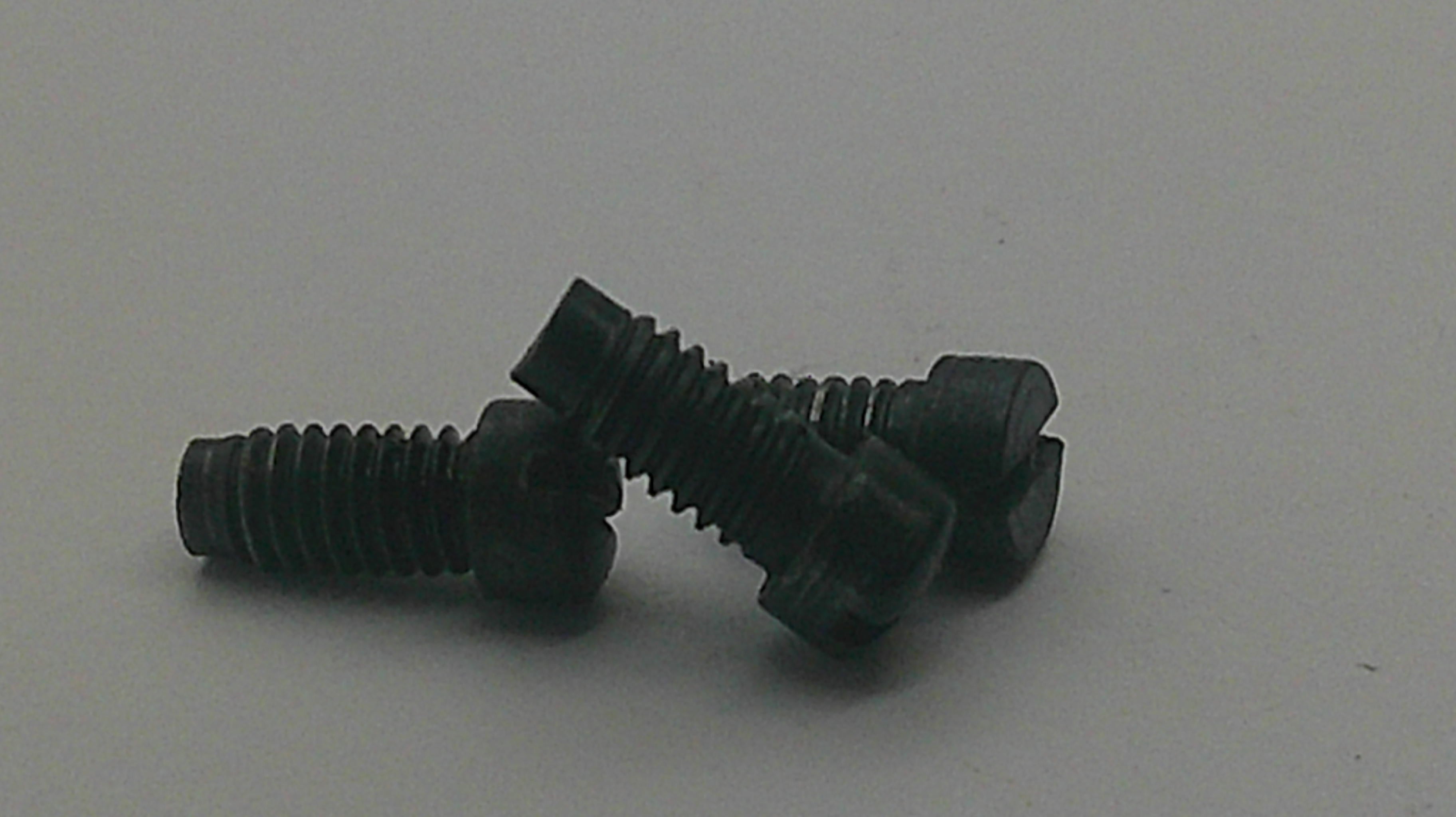 Three black metal flat-head hex screws with threaded shanks, arranged on a plain light gray background.