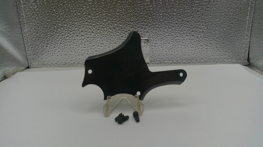 Black plastic component on a white stand with a textured gray background