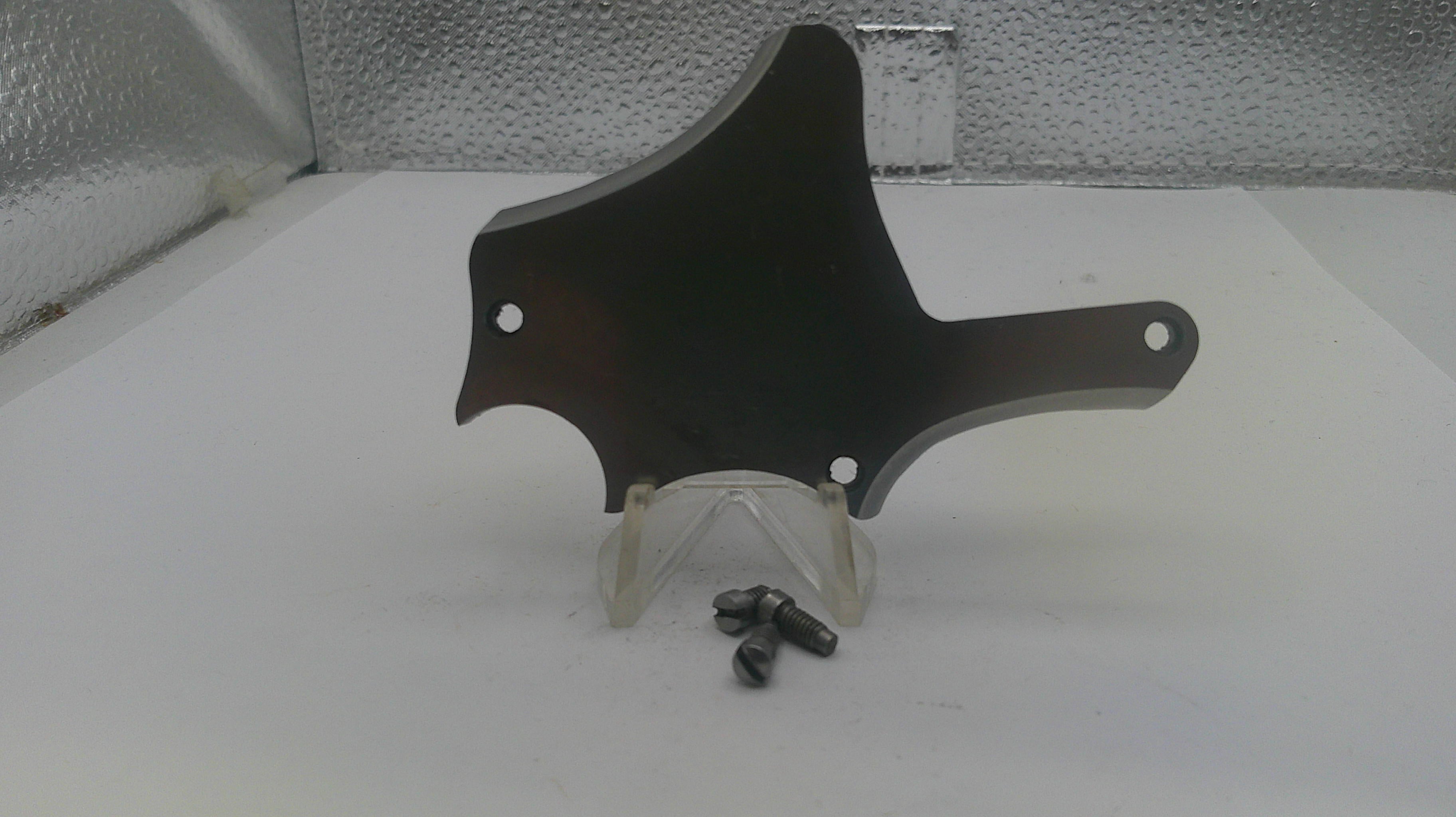 Black motorcycle part on a stand with screws on a white surface