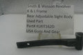A used black metal part for a Smith & Wesson revolver rear adjustable sight body, displayed on a clear stand with a white label card showing part details.