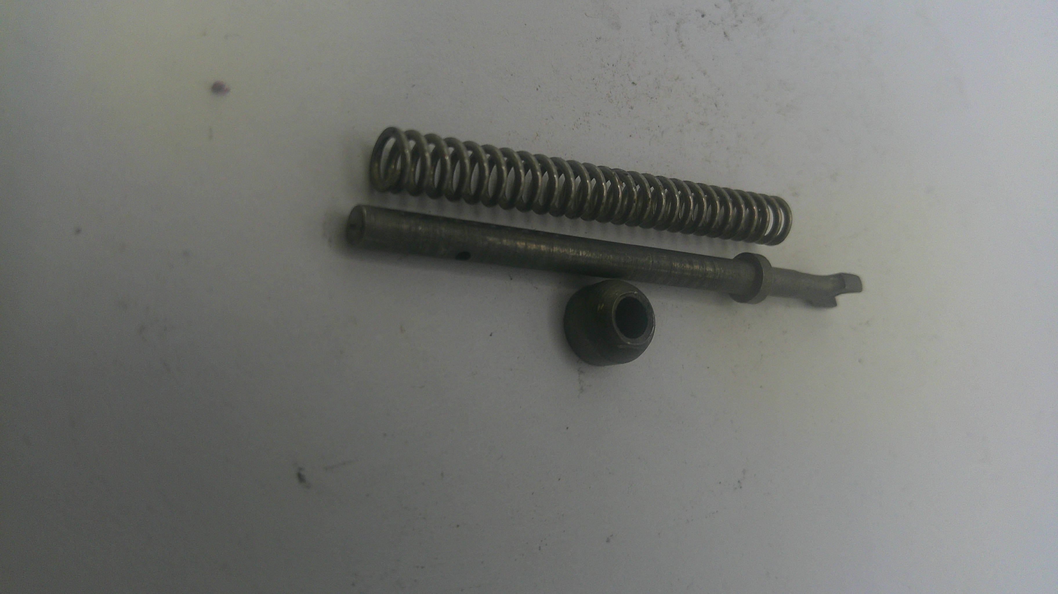Two metal springs and a cylindrical component on a white surface