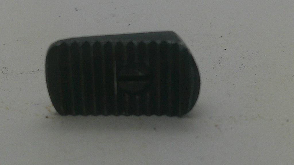 A small black textured plastic or rubber component with a central screw hole, photographed on a plain off-white surface.