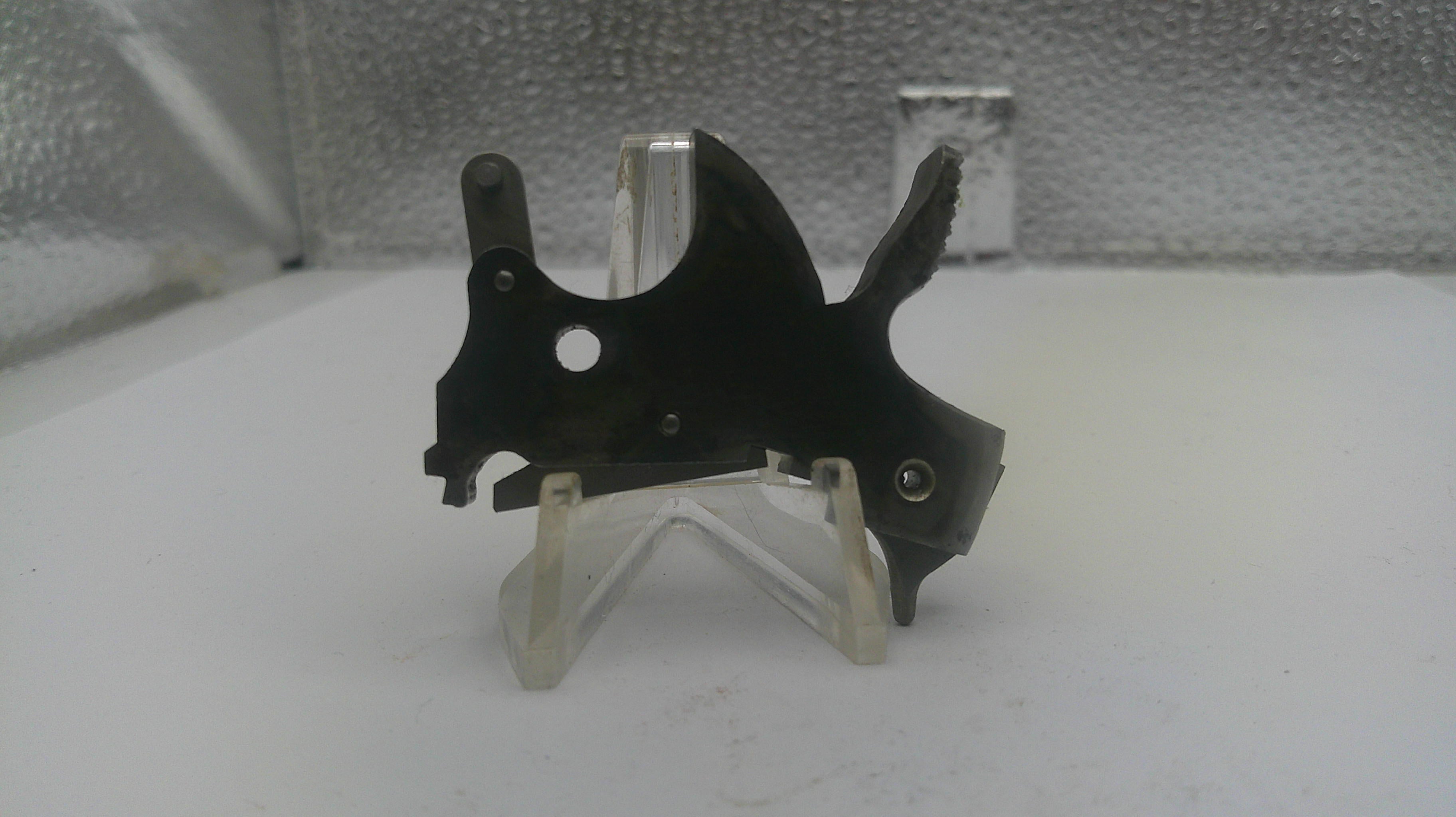 Black metal bracket on a clear stand against a textured white background