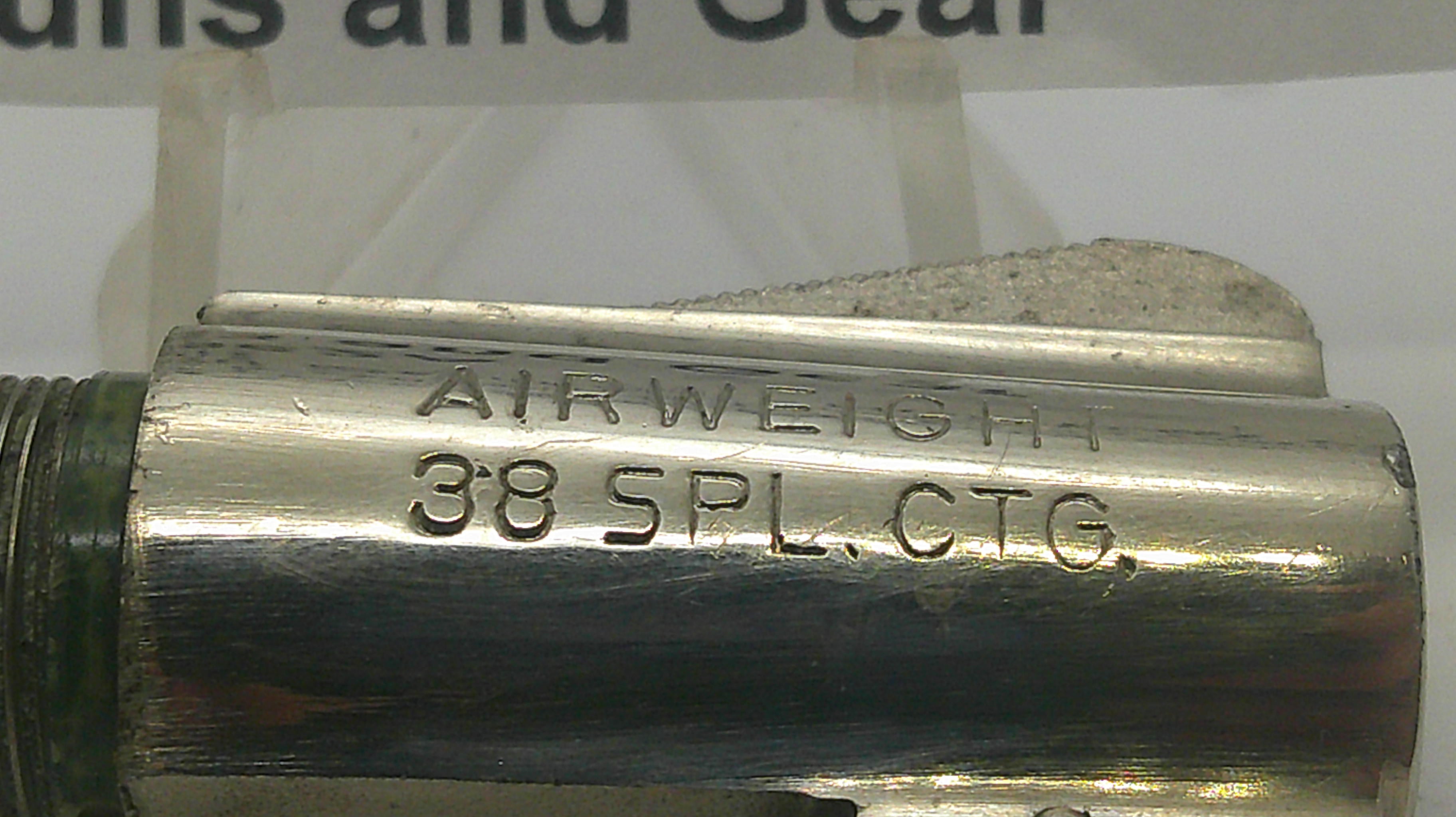 A close-up of a metallic cylindrical component with engraved text reading 'AIRWEIGHT 38 SPL CTG.' on a light background.