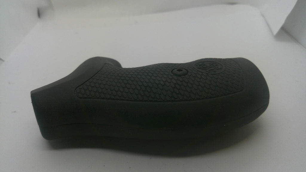 A black textured grip cover, likely for a firearm or tool handle, resting on a plain white surface.