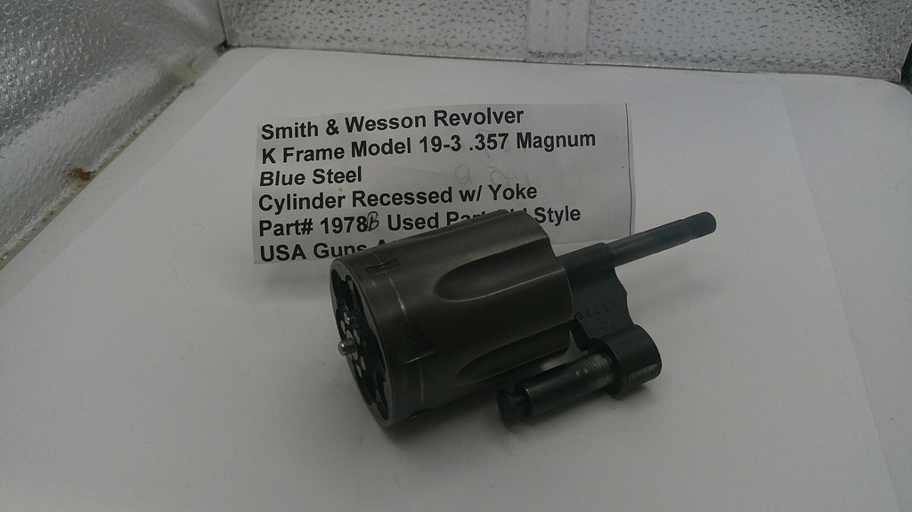 Smith & Wesson revolver cylinder on a white surface with descriptive text card.
