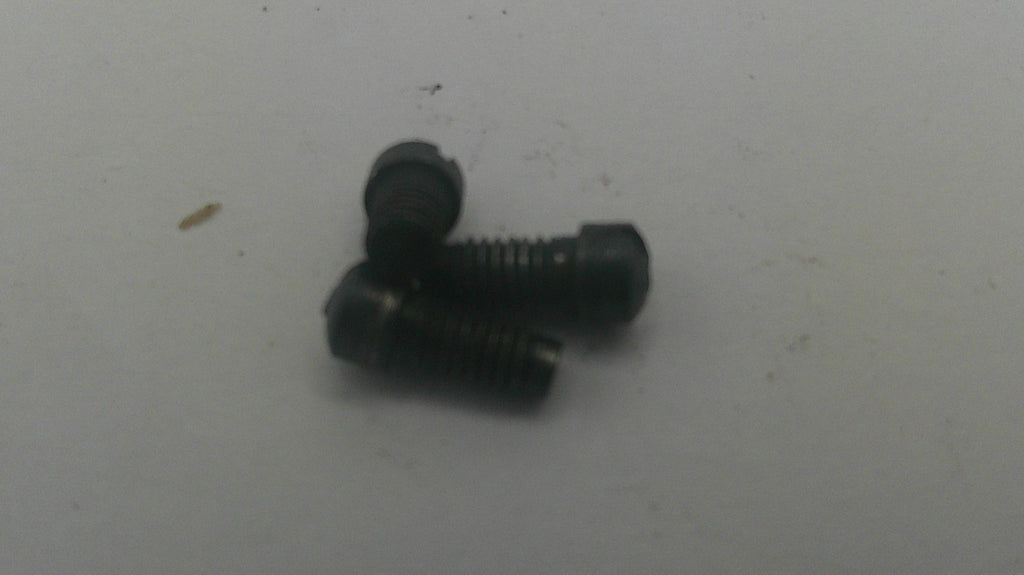 Three small black metal screws with slotted heads, arranged on a plain light gray surface.