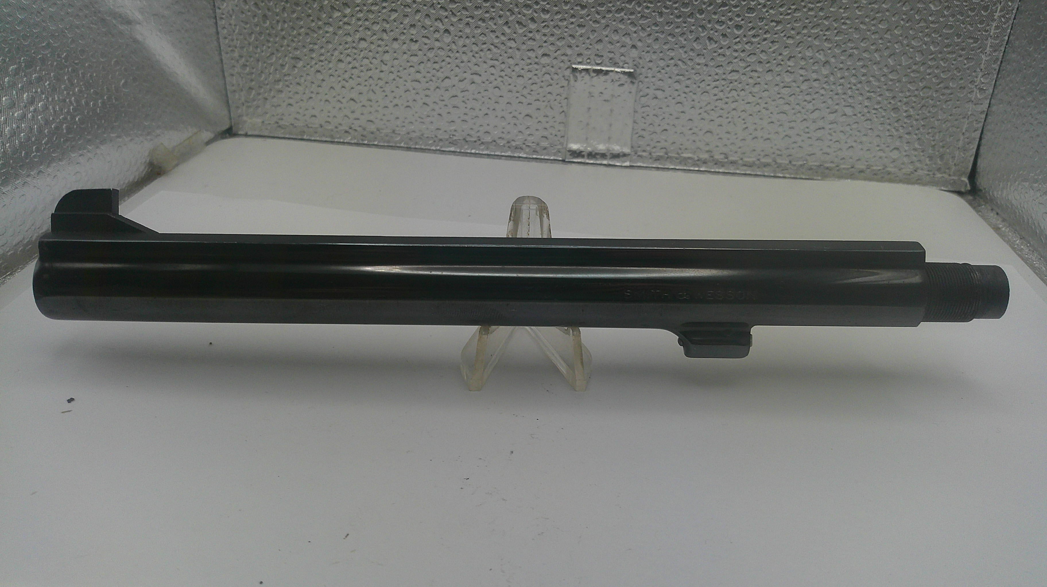A black metal cylindrical component, likely a barrel or tube, displayed horizontally on a small clear stand against a textured silver backdrop.