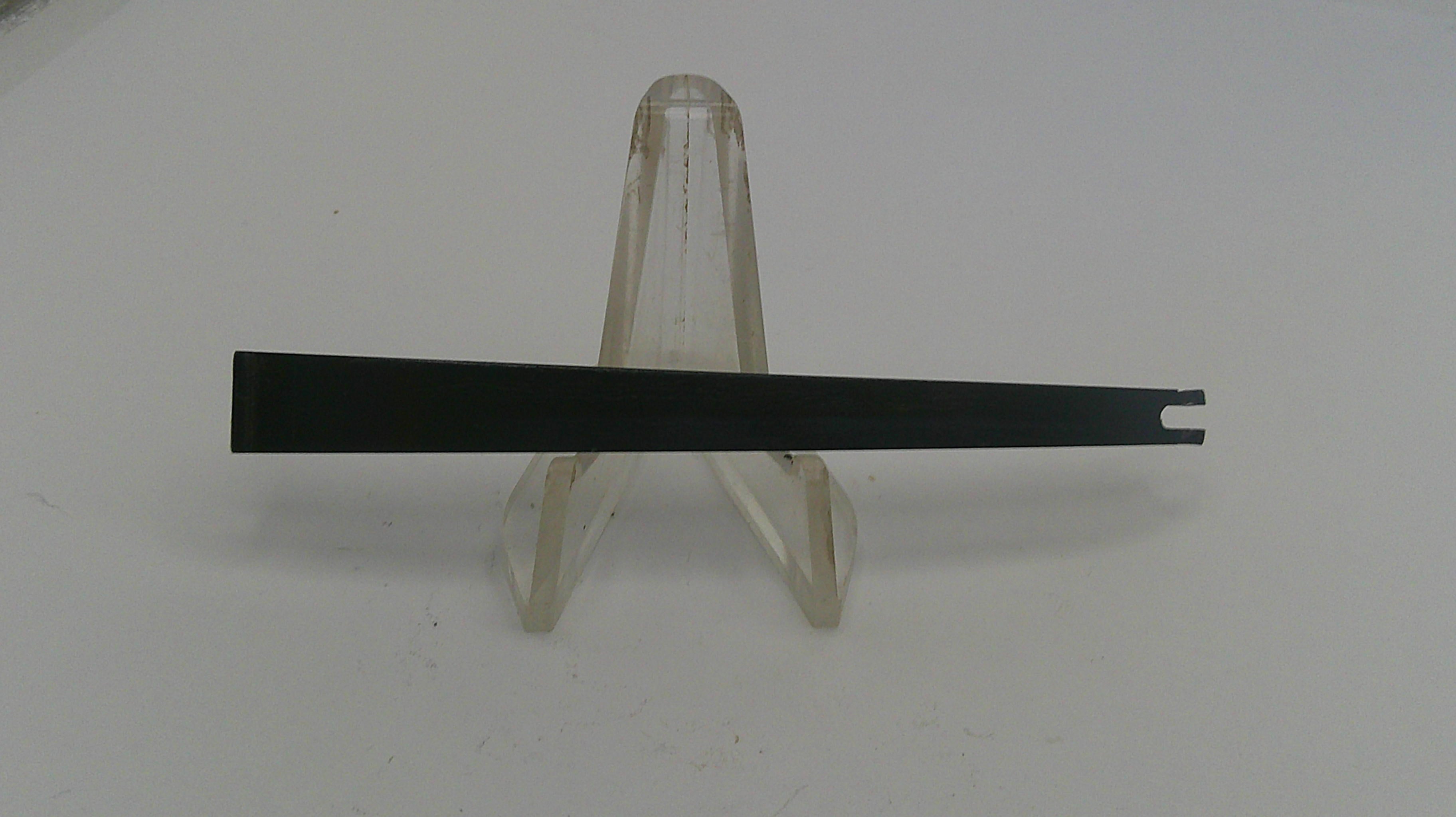 Black metal strip on a clear stand against a white background
