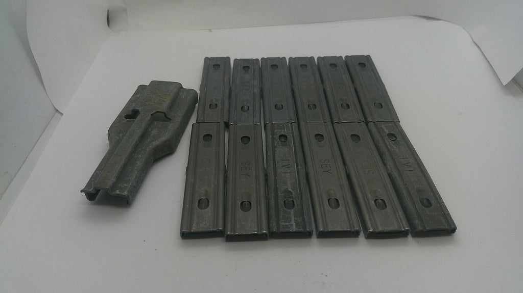 A set of dark gray metal guide rails or sliders, including one larger piece and nine matching narrow pieces, arranged on a white surface.