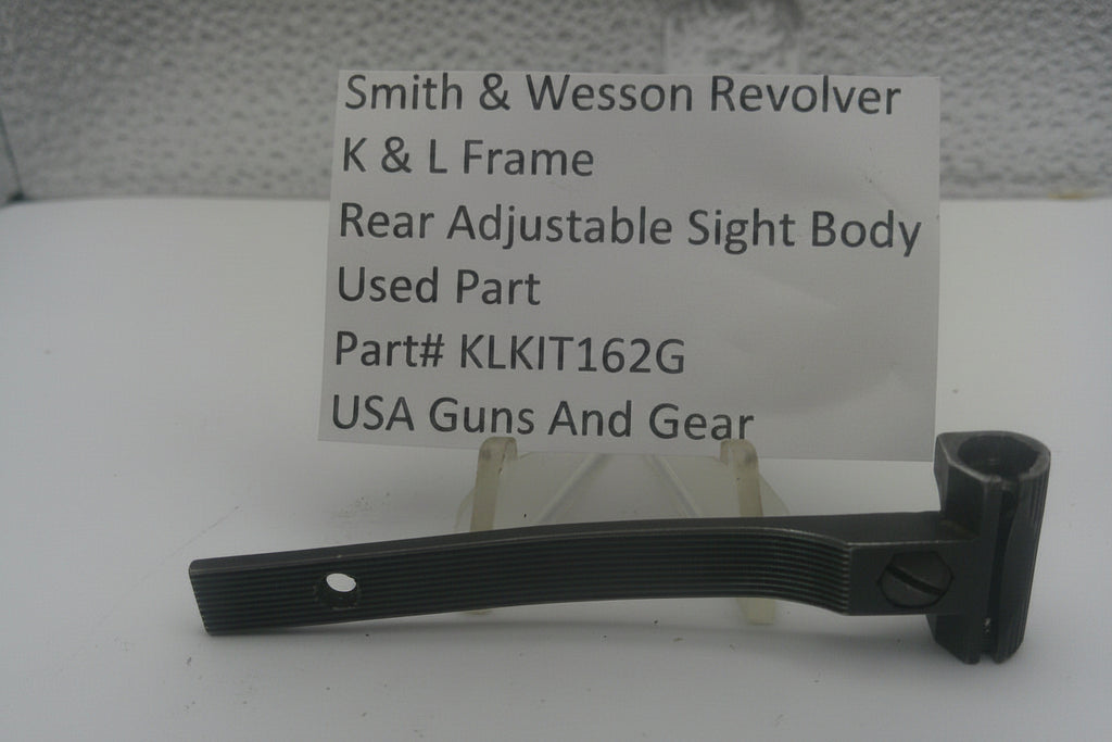A used black metal part for a Smith & Wesson revolver rear adjustable sight body, displayed on a clear stand with a white label card showing part details.