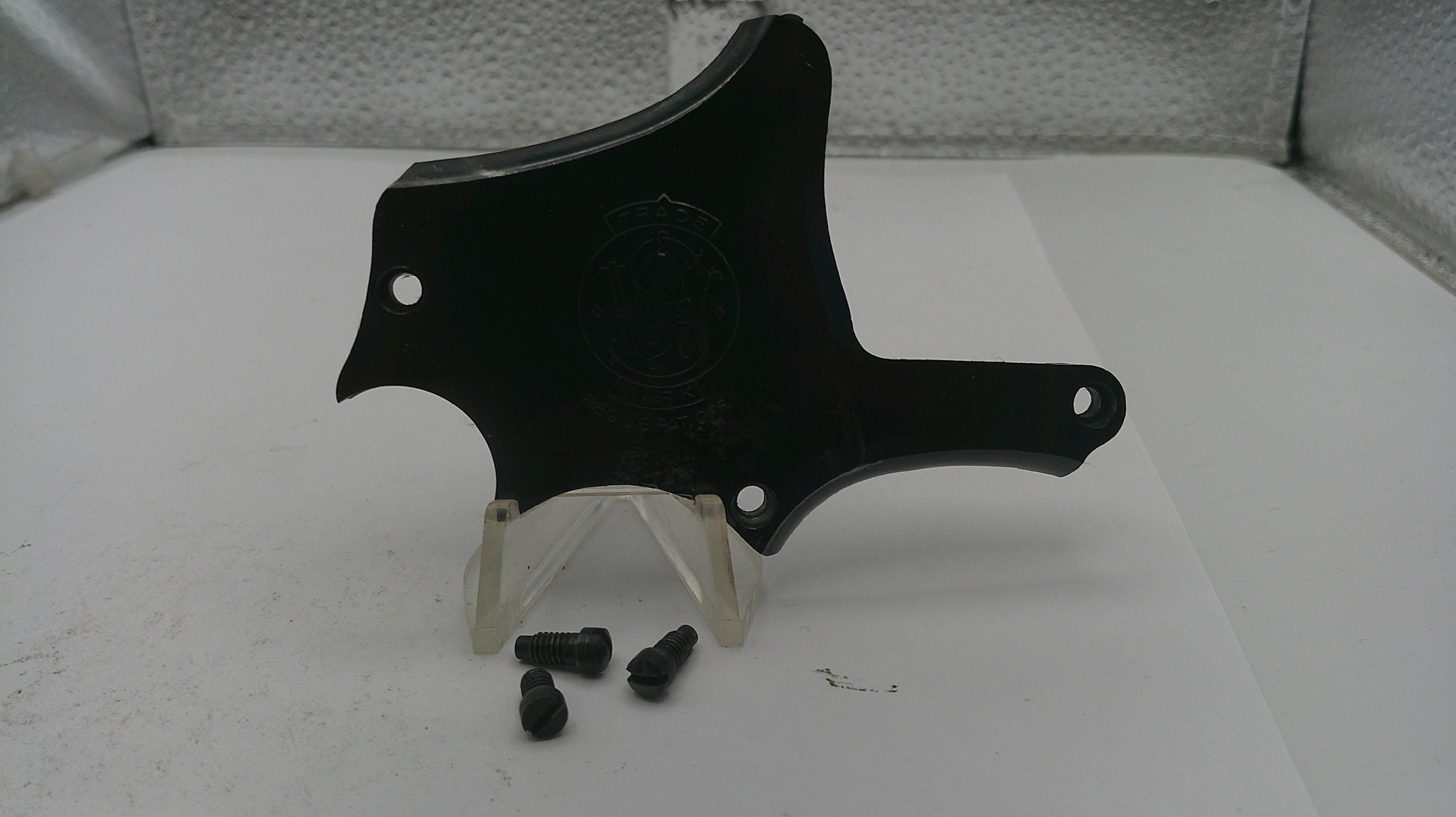 Black plastic car part on a white surface with screws