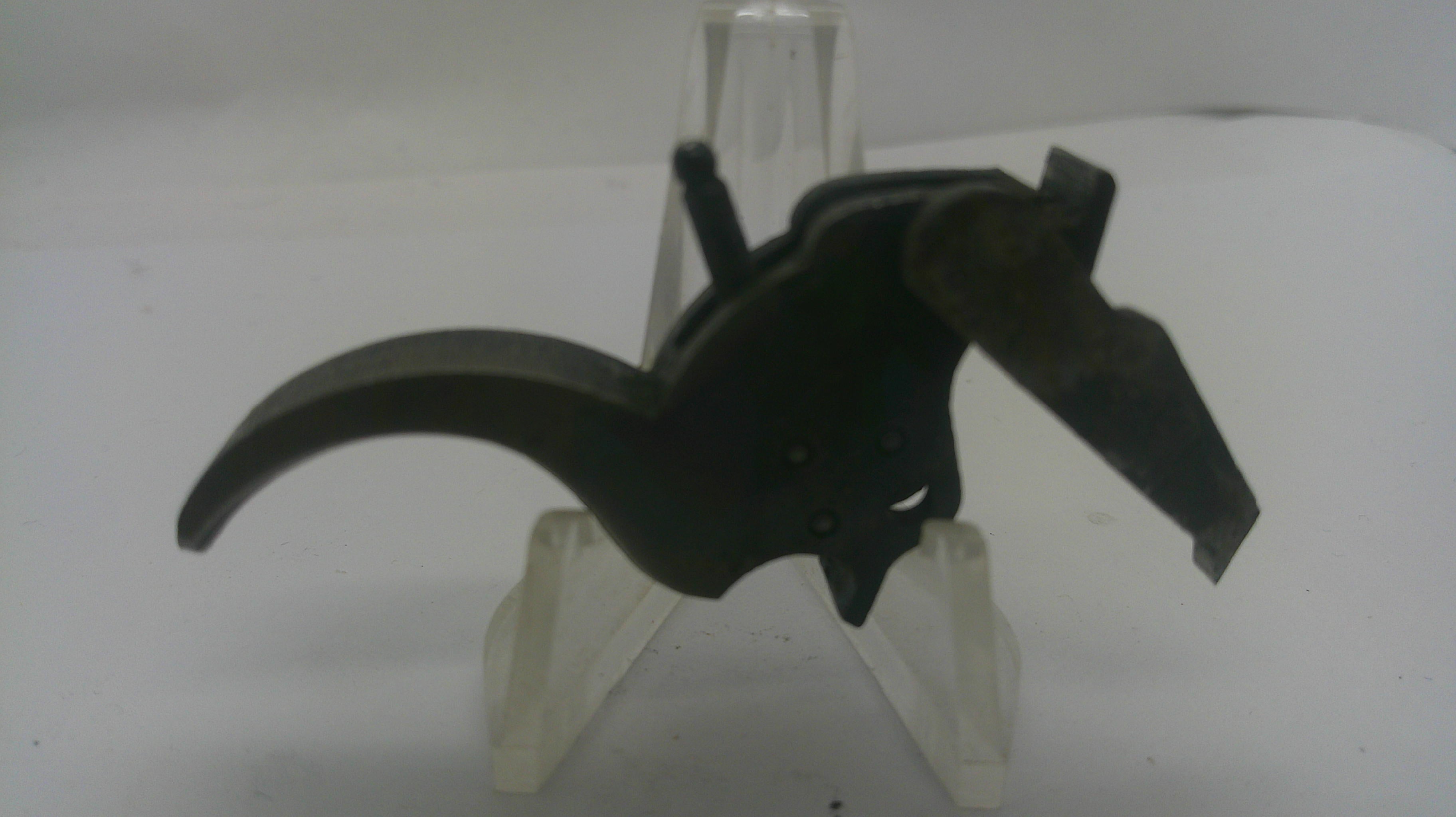 A black metal mechanical part, possibly a trigger or latch component, displayed on a clear plastic stand against a plain white background.