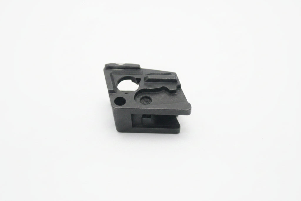 A small black plastic component or clip photographed on a plain off-white background.