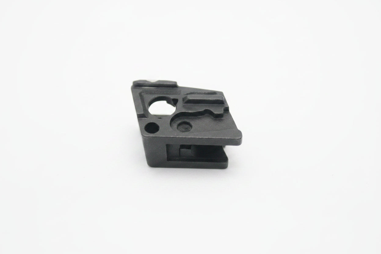 A small black plastic component or clip photographed on a plain off-white background.