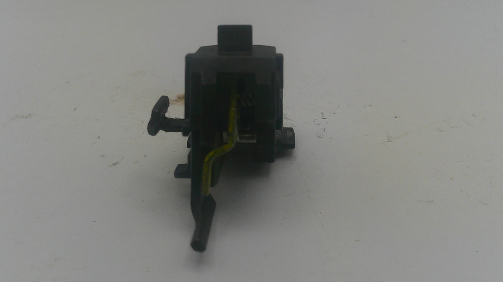 A small black plastic automotive or appliance switch component with a yellow wire attached, photographed on a plain light gray surface.