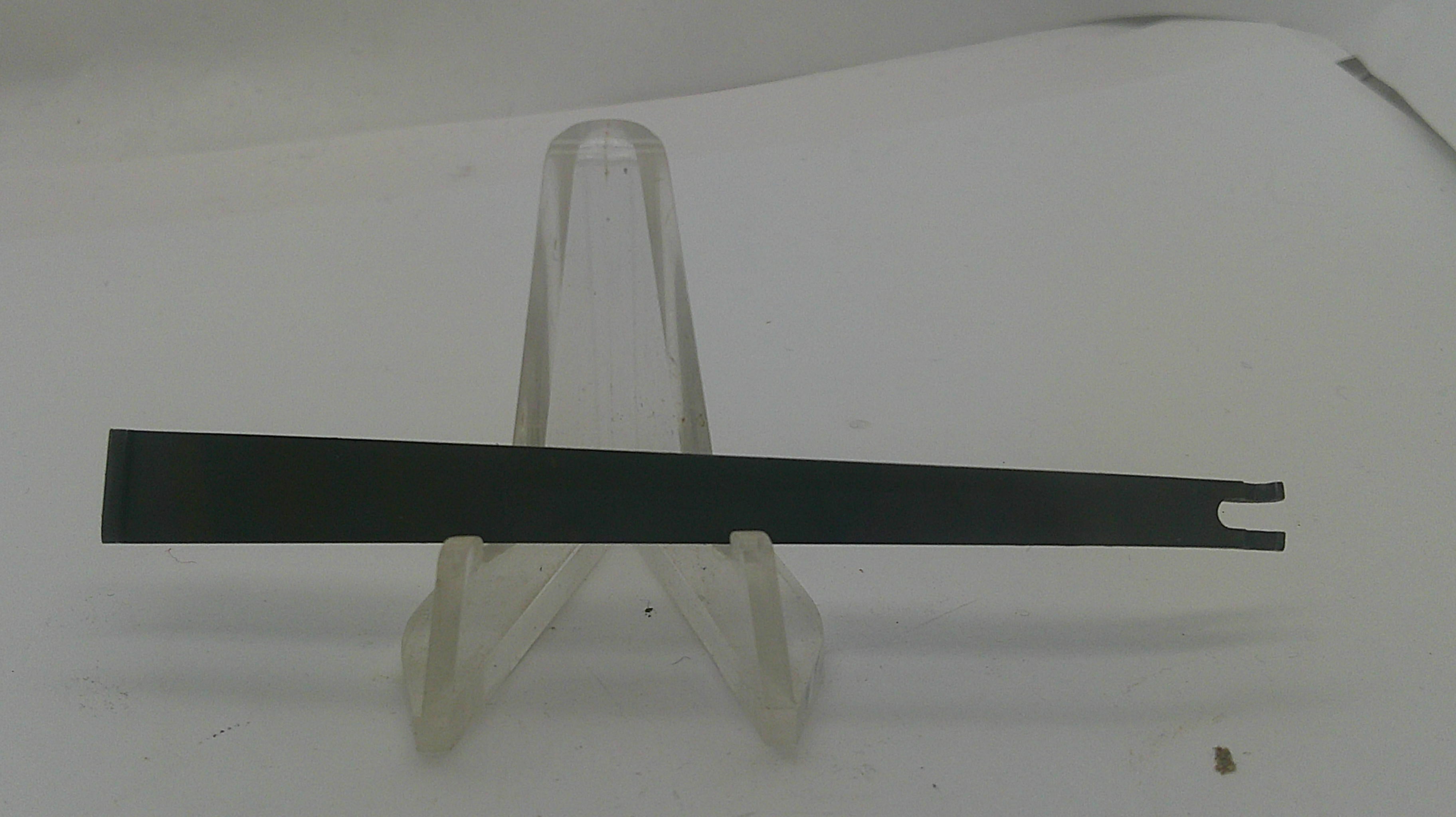 A long, thin black metal tool with a forked end, displayed horizontally on a clear plastic stand against a plain white background.