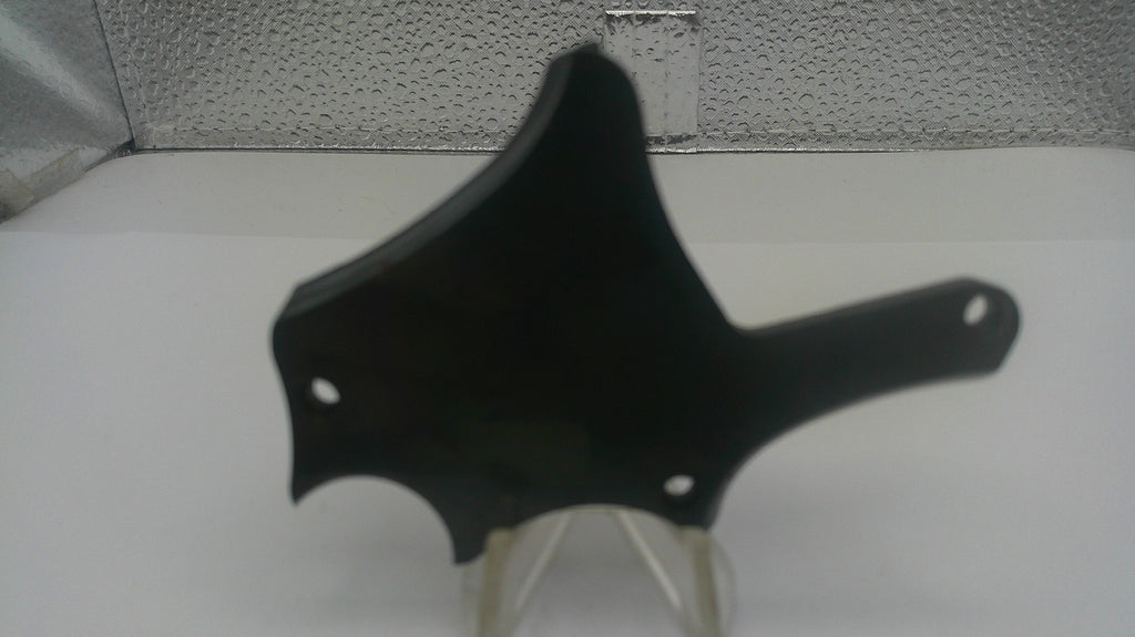 A black plastic motorcycle or scooter handlebar trim piece with mounting holes, displayed on a clear stand against a white surface and textured gray background.