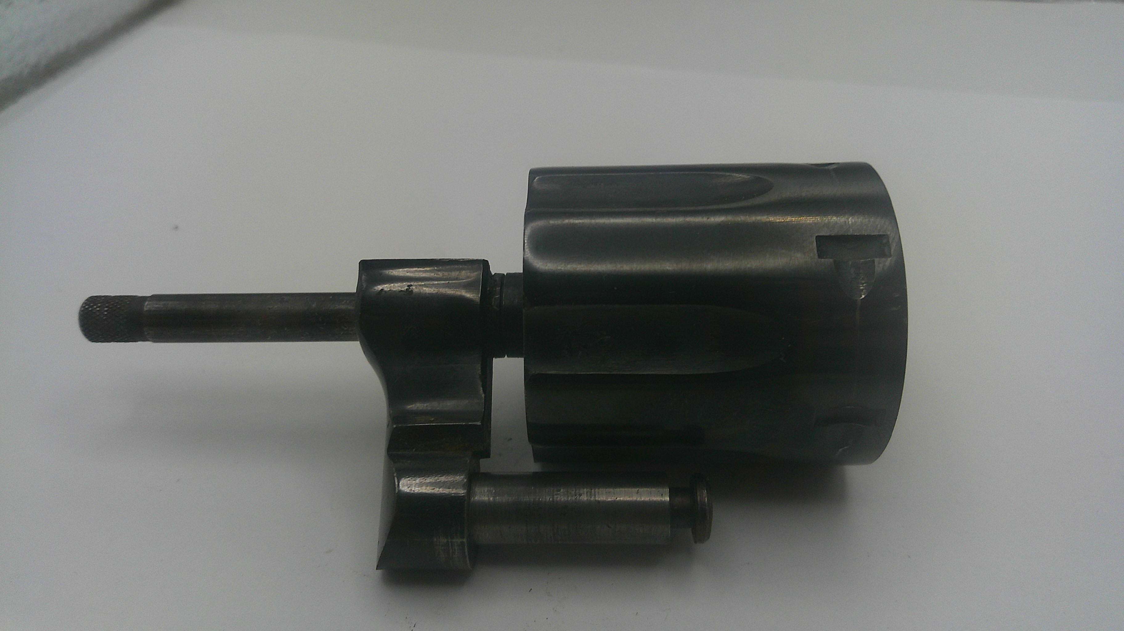 A dark metallic mechanical part, possibly a lock cylinder or hardware component, photographed on a plain white surface.