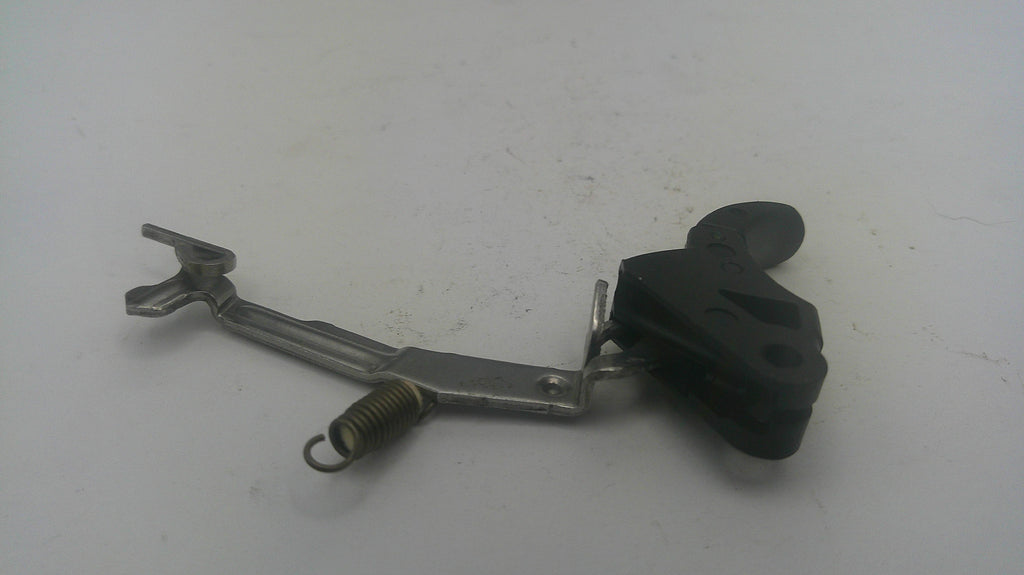 A used mechanical motorcycle or bicycle lever assembly with a black plastic grip, silver metal arm, and a small coiled spring, shown on a plain light gray surface.