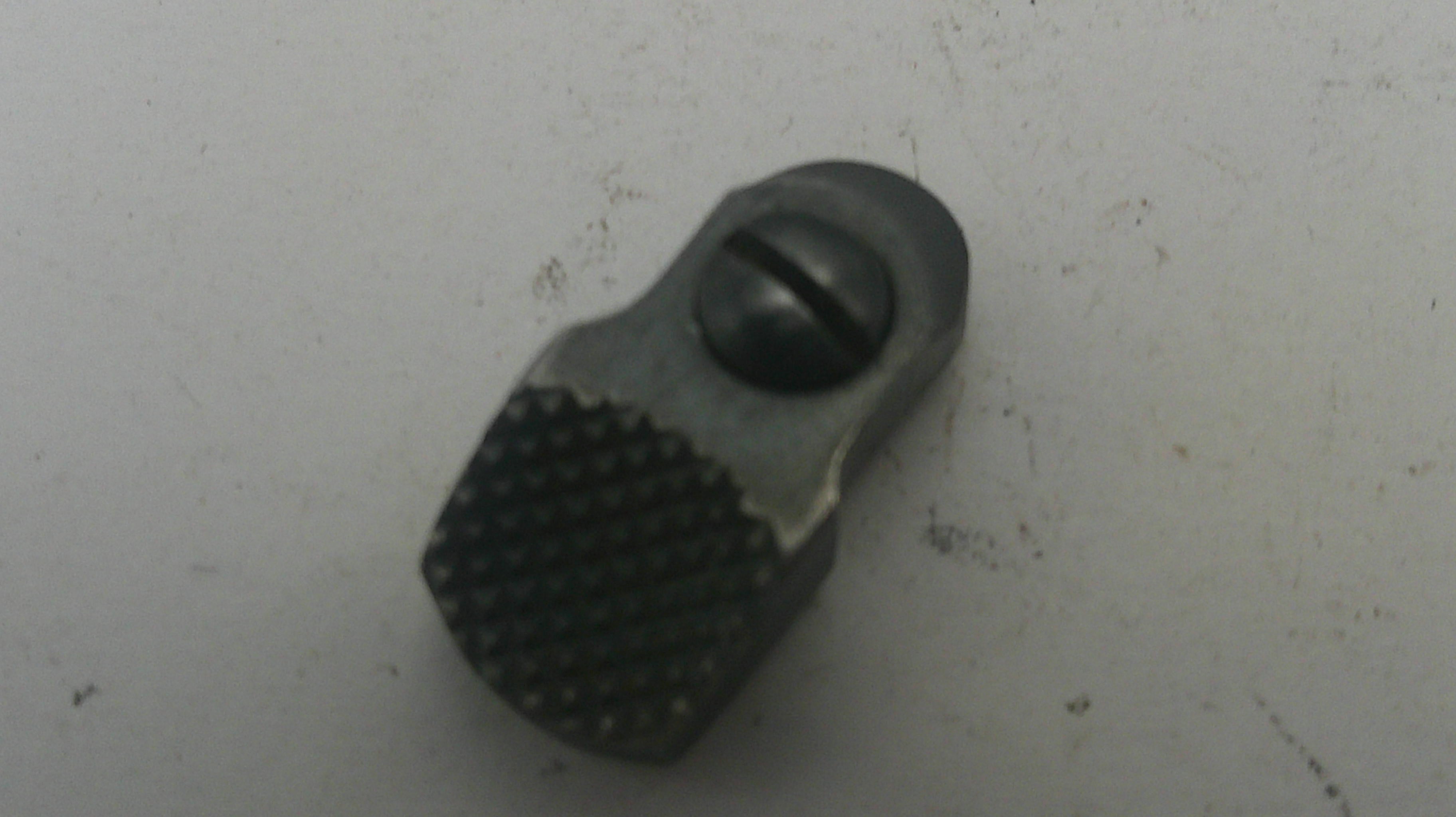 Small metallic object with textured surface on a light gray background