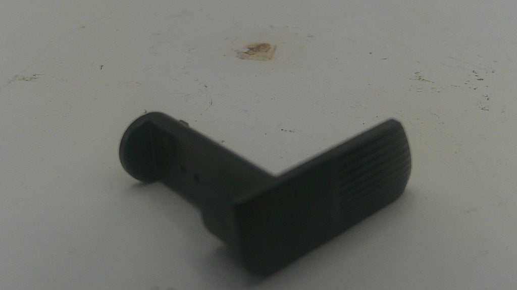 A small black plastic L-shaped component with a textured side, photographed on a light gray surface.