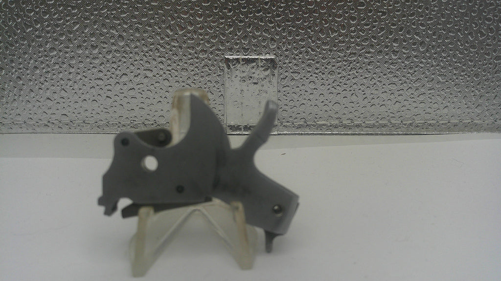 Small gray mechanical object on a stand against a textured silver background