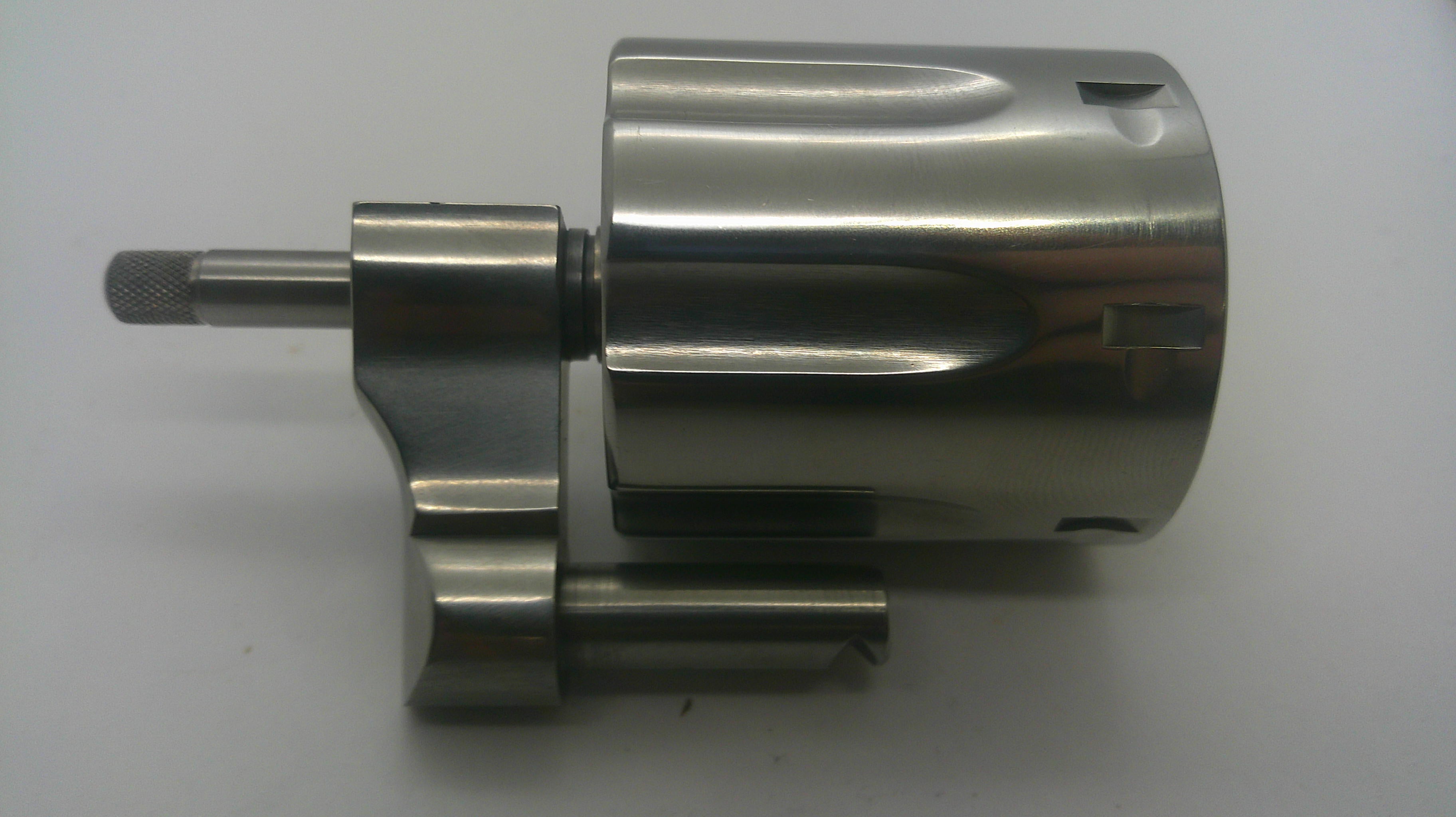 A machined metallic cylindrical component with a short shaft and mounting bracket, photographed on a plain light background.
