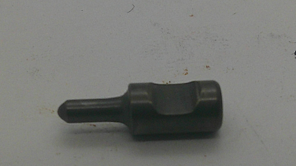 A dark metallic flathead screwdriver bit with a hex shank, resting on a light gray surface.