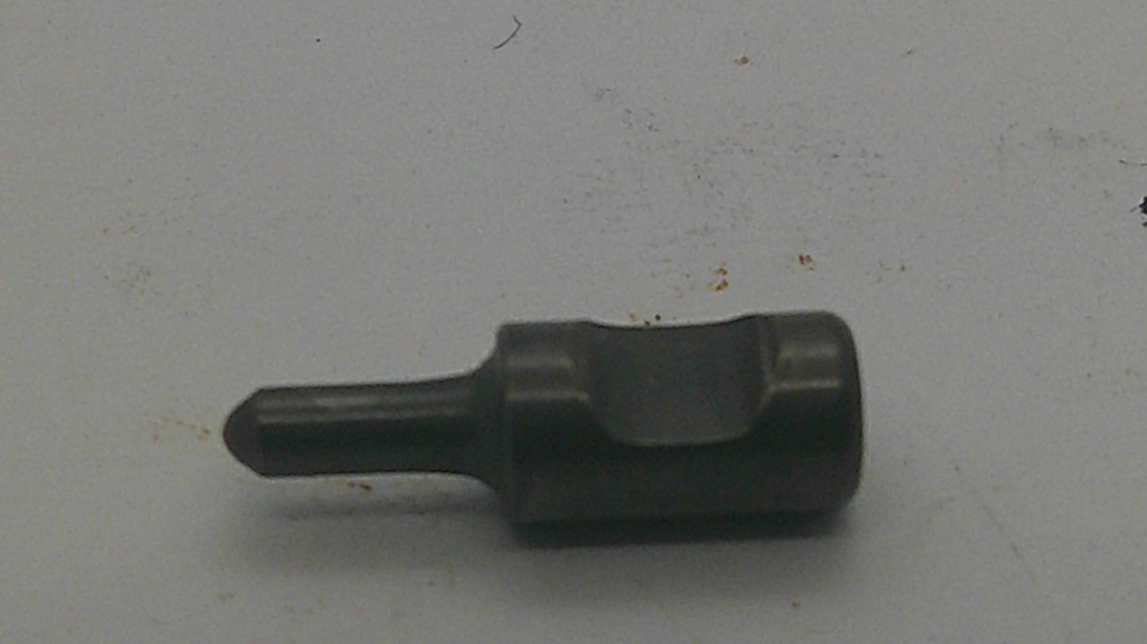 A dark metallic flathead screwdriver bit with a hex shank, resting on a light gray surface.